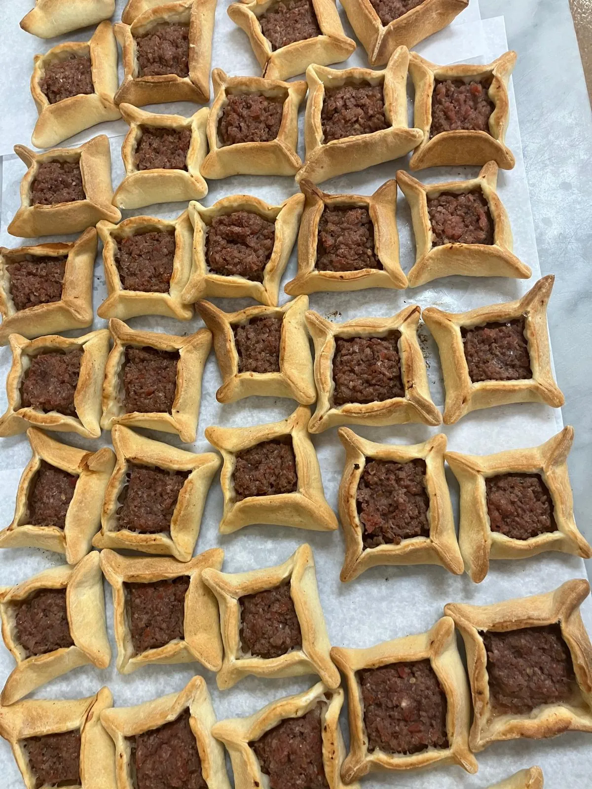 Handmade sfiha meat pies being prepared for catering