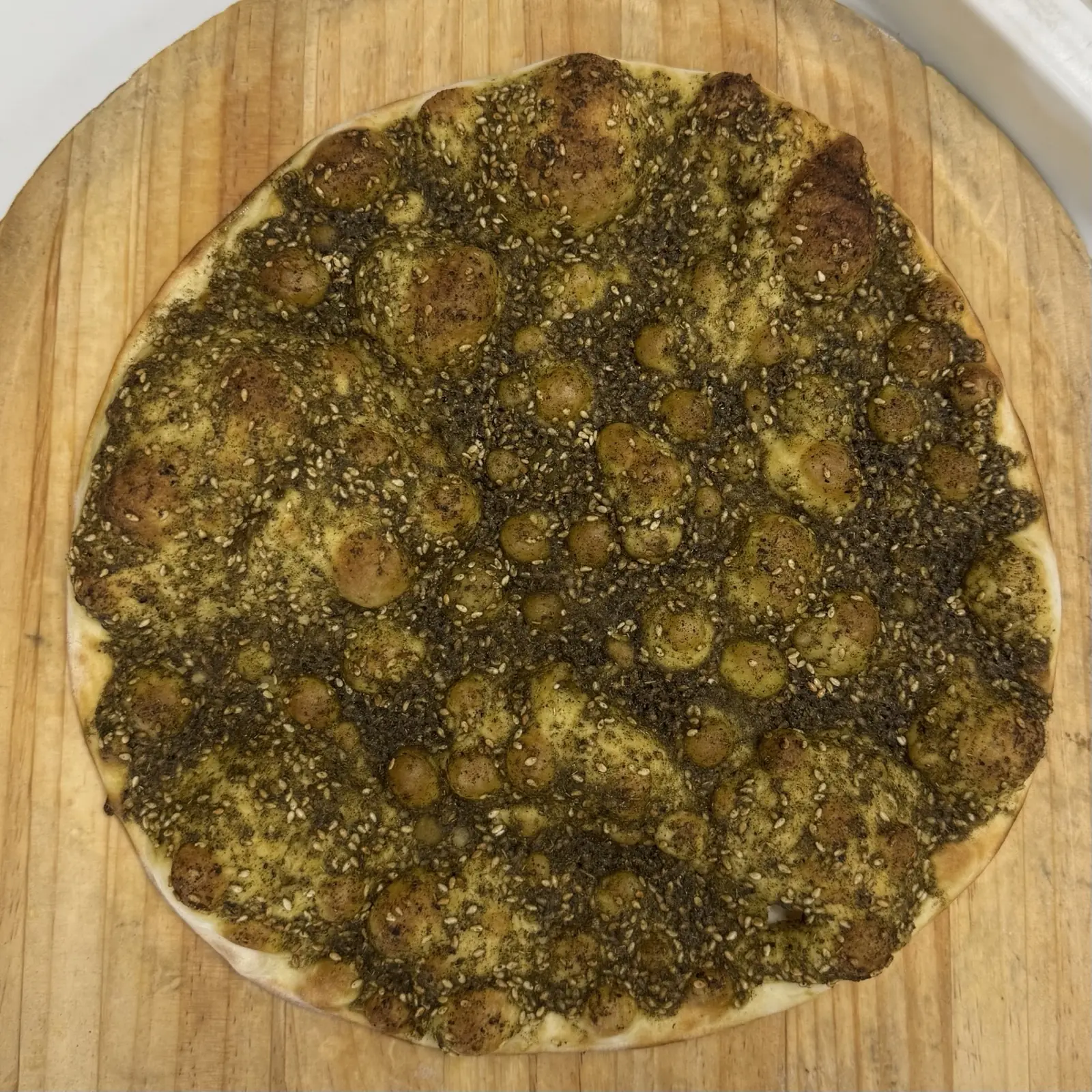 Fresh zaatar manoushe on a cutting board at Adonis Market